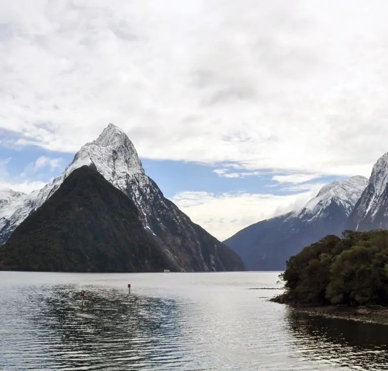 Mitre Peak in Milford Sound with snow on the mountains during a clear winter day.